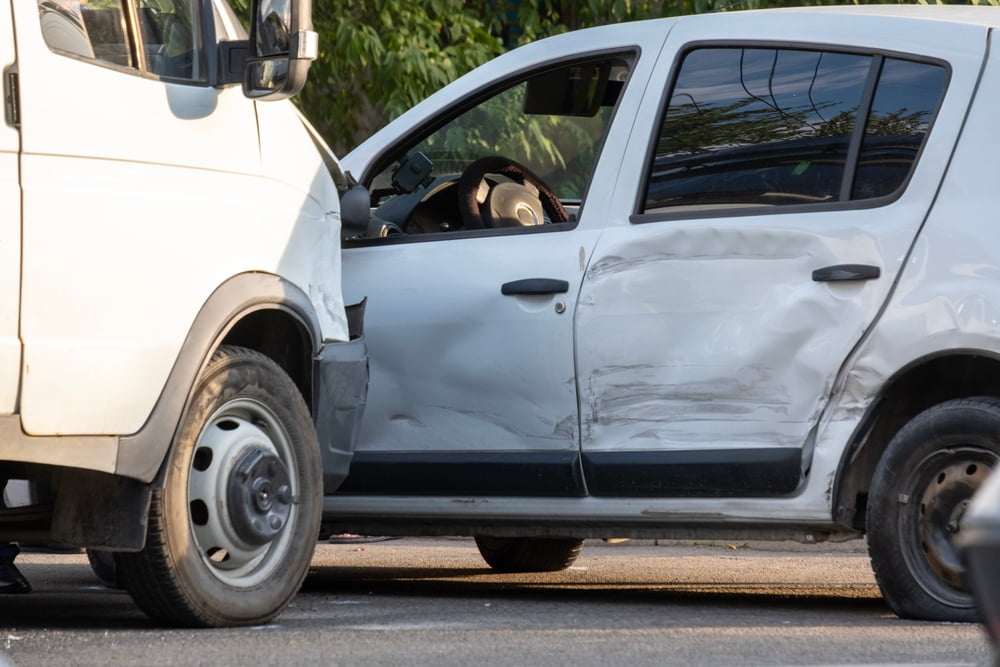 Passenger vehicle with severe side damage after being struck by a commercial van in a side-impact collision.