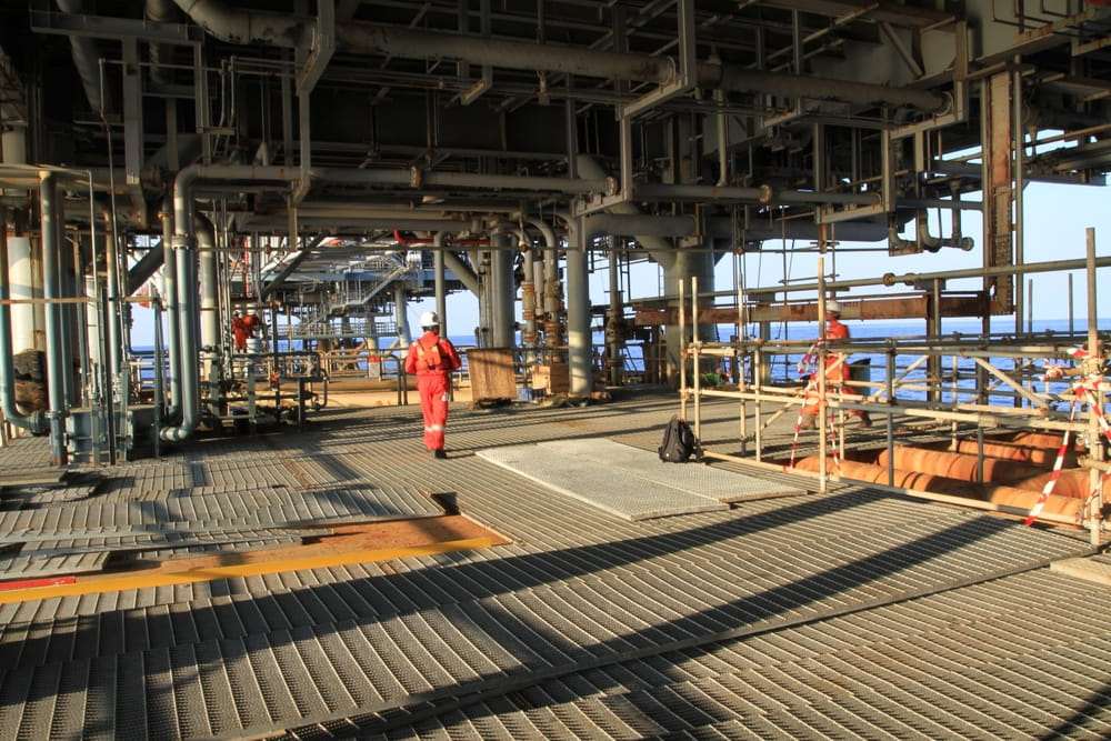 Worker in red coveralls walking across an offshore oil rig platform, representing injuries on a Gulf Coast oil rig