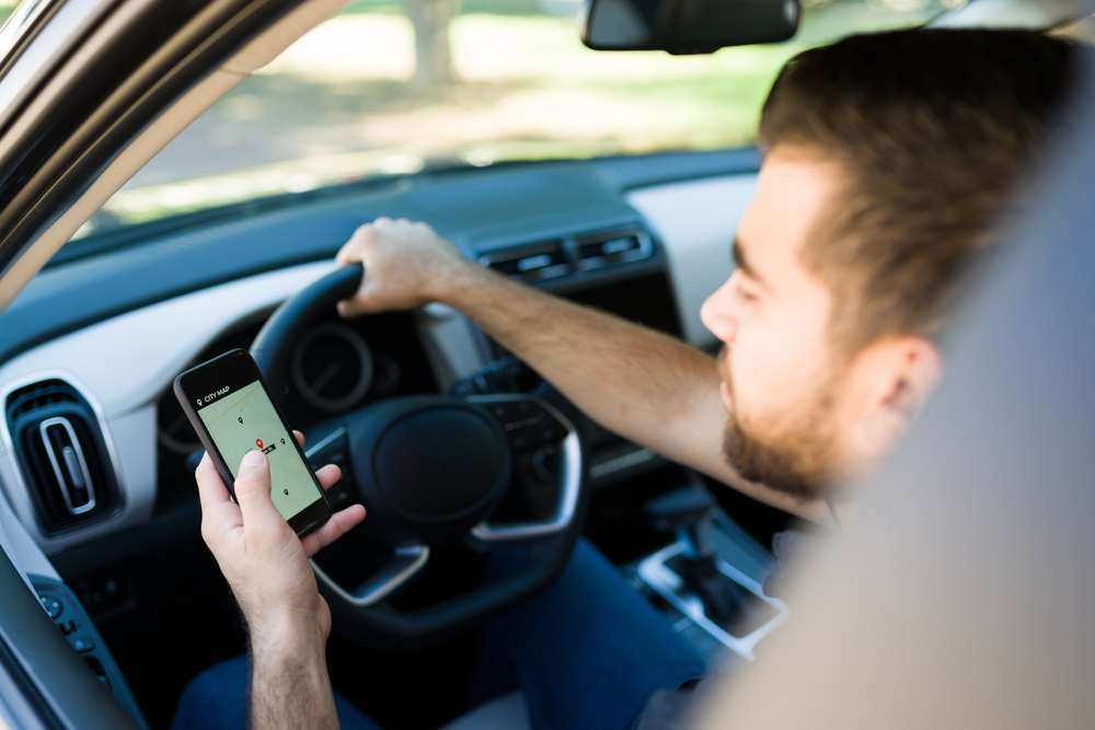 Rideshare driver viewing a GPS navigation app on a smartphone before starting a trip.