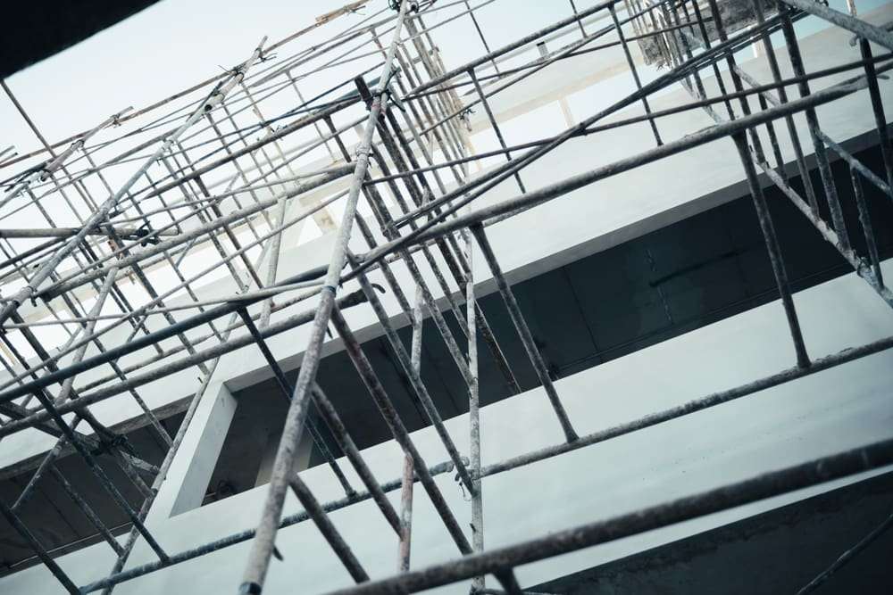 Metal scaffolding installed around a multi-story building under construction.