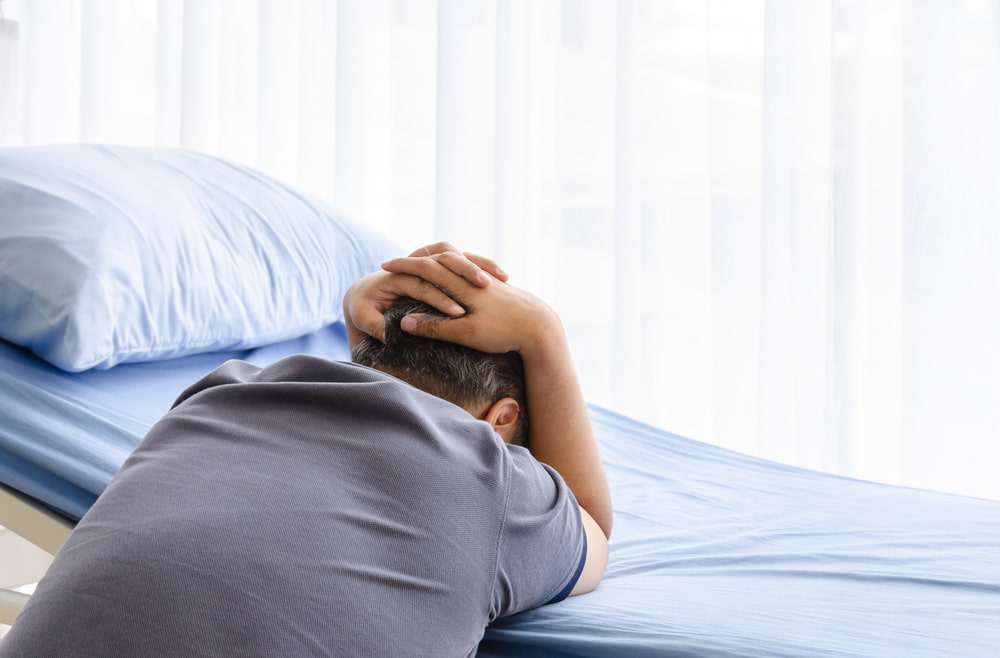 Grieving family member sitting beside a hospital bed after the loss of a loved one in a fatal accident.