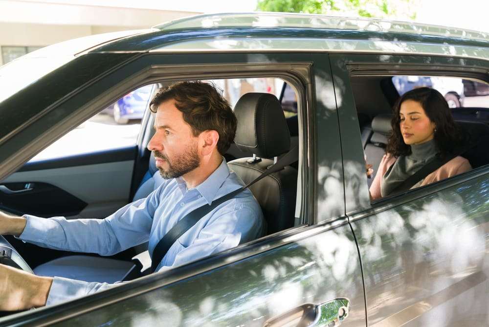 Female passenger using a smartphone while riding in the back seat of a rideshare vehicle.