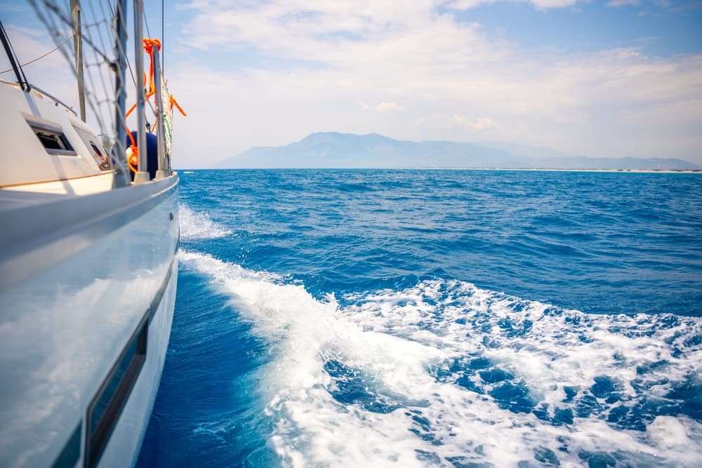 Recreational boat traveling across open water with a coastline visible in the distance